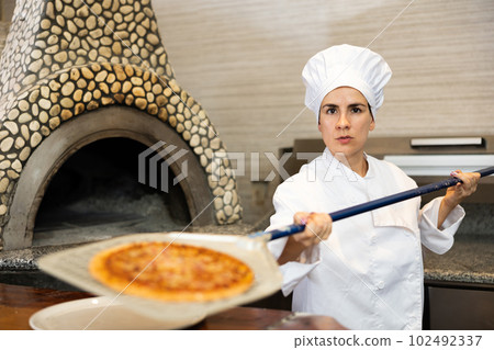 Woman pizza chef at work in restaurant Woman pizza chef at work in restaurant 102492337