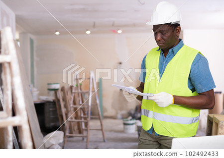 Portrait of confident foreman in a yellow vest with documents in hands 102492433