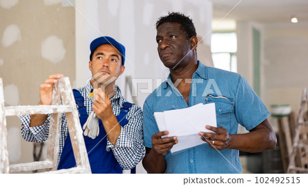 Construction manager talking with employed repairman 102492515