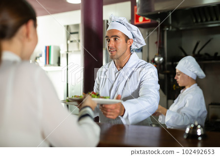 Service process in cafe - chef serves ready meals to visitors of modern restaurant 102492653