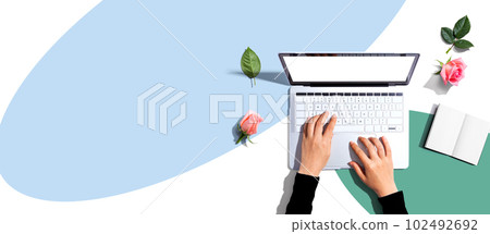 Woman using her laptop with pink roses 102492692