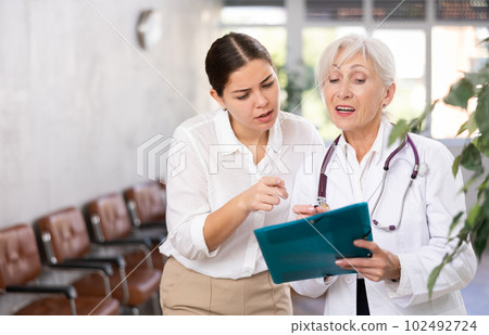 Elderly woman doctor and young woman with documents folder Elderly woman doctor and young woman with documents folder 102492724