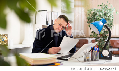 Male clerical worker sitting at table in office 102492871