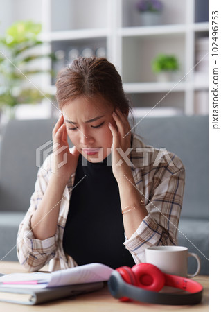 Stressed woman sits on sofa at home, studying and analyze house bills and submitting tax forms. Stressed woman sits on sofa at home, studying and analyze house bills and submitting tax forms. 102496753