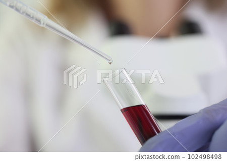 Scientist woman dropping transparent liquid into flask, tests in laboratory 102498498