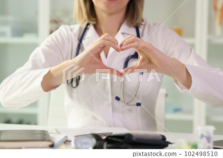 Woman doctor showing heart shape sign with hands Woman doctor showing heart shape sign with hands 102498510