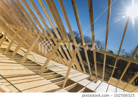 Construction framework timber truss framed building is currently being constructed with rafters, roof beams wooden joists as part of construction framework Construction framework timber truss framed building is currently being constructed with rafters, roof beams wooden joists as part of construction framework 102500325