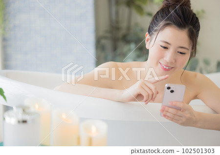 Female beauty A young woman looking at her smartphone while taking a bath Female beauty A young woman looking at her smartphone while taking a bath 102501303