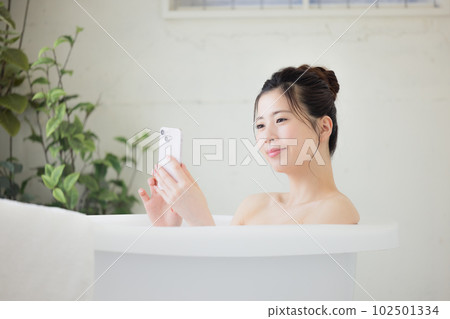 Female beauty A young woman looking at her smartphone while taking a bath Female beauty A young woman looking at her smartphone while taking a bath 102501334