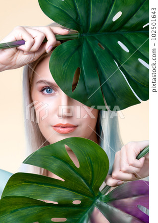 Closeup facial portrait personable woman holding green monstera. Closeup facial portrait personable woman holding green monstera. 102501643