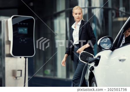 Focus EV charging station for electric car with blur progressive businesswoman. 102501736
