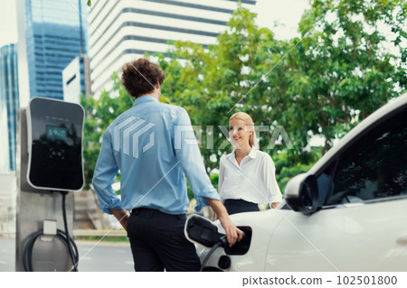 Progressive businessman and businesswoman at charging point and EV car 102501800