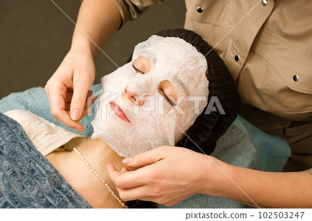 Acne treatment at beautician. Applying sheet mask 102503247