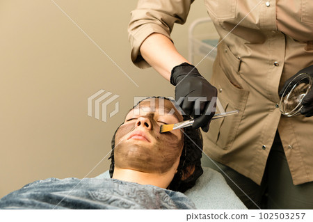 Cosmetologist apply carbon nanogel to face client 102503257