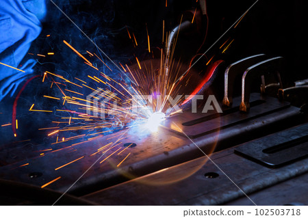 Worker in heavy industry wearing protective clothing wearing on argon welding mask to weld steel an factorie 102503718
