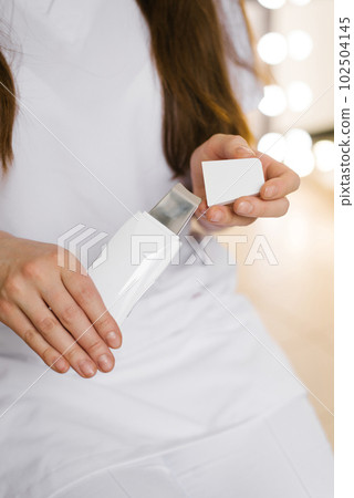 Close-up of a cosmetologist woman opening a device for ultrasonic facial cleansing Close-up of a cosmetologist woman opening a device for ultrasonic facial cleansing 102504145