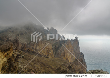 Dead city in fog and clouds. Khoba-Tele Ridge of Karadag Reserve in spring. Crimea Dead city in fog and clouds. Khoba-Tele Ridge of Karadag Reserve in spring. Crimea 102504382