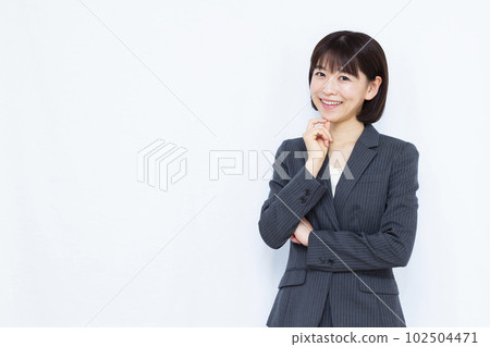 一個三十多歲的女人，穿著西裝，在白色背景前微笑著思考 102504471