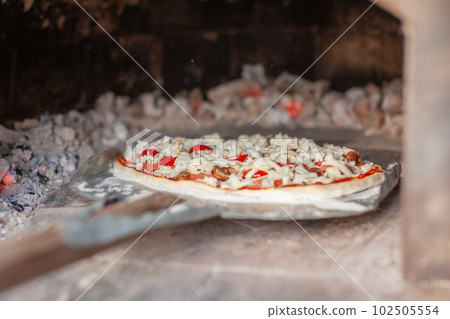 Cooking real pizza in a brick oven. Wood and fire are burning Cooking real pizza in a brick oven. Wood and fire are burning 102505554