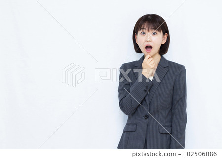 一位穿著西裝的三十多歲的女人，在白色背景前微笑著感到驚訝 102506086
