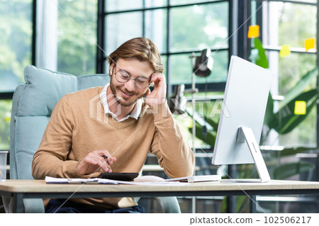 Businessman in shirt doing paperwork, man working with documents, contracts and bills sitting at table using laptop at work, financier accountant with beard and glasses Businessman in shirt doing paperwork, man working with documents, contracts and bills sitting at table using laptop at work, financier accountant with beard and glasses 102506217