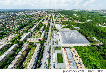 Aerial city view with crossroads and roads, houses, buildings, parks and parking lots. Sunny summer panoramic image 102507094