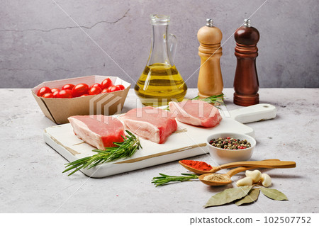 Three raw pork escalopes on cutting board Three raw pork escalopes on cutting board 102507752