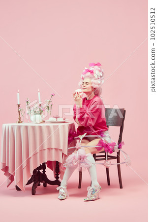 Portrait gorgeous hungry queen wearing big pink wig holding marshmallow with exciting face on pink studio background. Yummy cake Portrait gorgeous hungry queen wearing big pink wig holding marshmallow with exciting face on pink studio background. Yummy cake 102510512