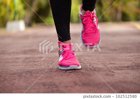 Fitness woman training and jogging in summer park, close up on running shoes in sunlight. Healthy lifestyle Fitness woman training and jogging in summer park, close up on running shoes in sunlight. Healthy lifestyle 102512580