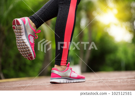 Fitness woman training and jogging in summer park, close up on running shoes in sunlight. Healthy lifestyle 102512581