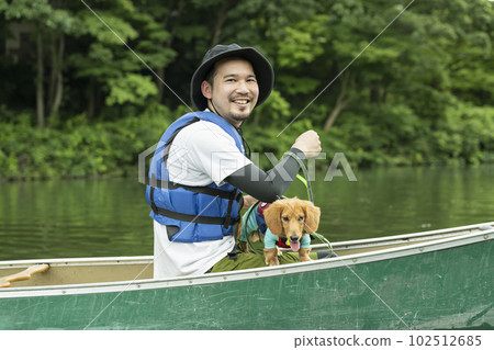 A man enjoys kayaking down the river with his dog 102512685