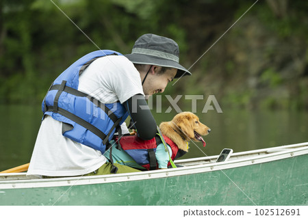 A man enjoys kayaking down the river with his dog A man enjoys kayaking down the river with his dog 102512691