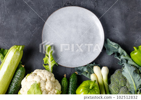 Border of green raw vegetables around empty plate. Place for your product or text. Border of green raw vegetables around empty plate. Place for your product or text. 102512832