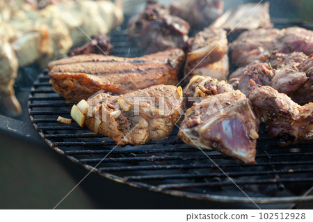 Cooking different meat on barbecue. Grilled and roasted lamb steaks on bbq Cooking different meat on barbecue. Grilled and roasted lamb steaks on bbq 102512928