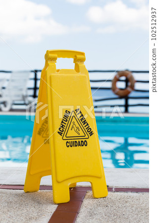Wet floor warning sign near a swimming pool at poolside 102512937