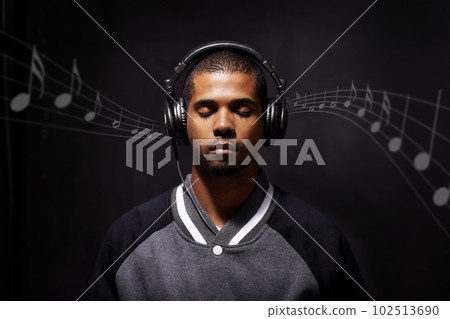 Overlay, music and notes with a man streaming audio in studio on a dark background for peace or escape. Digital, rhythm or beat and a handsome young male listening to the radio with his eyes closed Overlay, music and notes with a man streaming audio in studio on a dark background for peace or escape. Digital, rhythm or beat and a handsome young male listening to the radio with his eyes closed 102513690