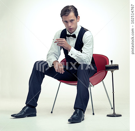 A gentleman knows. A studio portrait of a stylish young gentleman smoking a cigarette in a vintage setting. A gentleman knows. A studio portrait of a stylish young gentleman smoking a cigarette in a vintage setting. 102514767