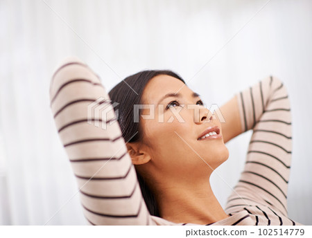 Another successful day at the office. an attractive asian businesswoman leaning back with her arms behind her head. 102514779