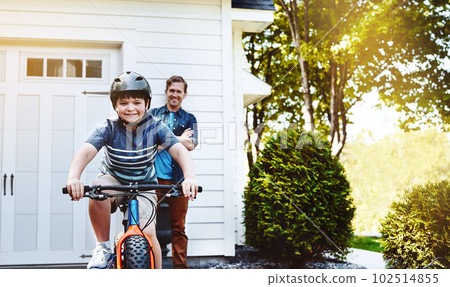 Look Dad No more training wheels. a young boy riding a bicycle with his father in the background. 102514855