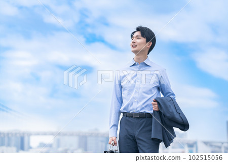 一位年輕的商人穿著脫衣夾克清爽地行走 一位年輕的商人穿著脫衣夾克清爽地行走 102515056