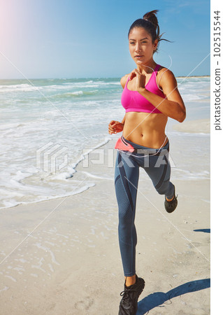 Taking her workout outdoors. an attractive young woman working out on the beach. 102515544