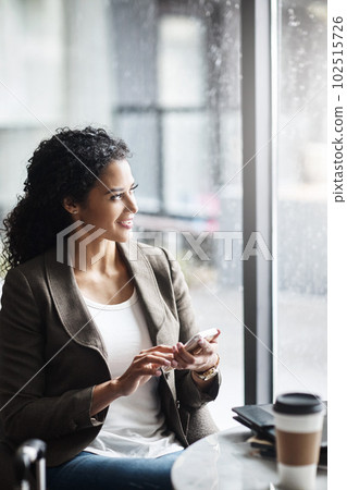 Taking care of some business before she takes flight. a young businesswoman using a cellphone while waiting for her flight in an airport lounge. 102515726