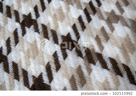 Knitted wool scarf with beige and brown pattern. Close-up texture with geometric pattern 102515992