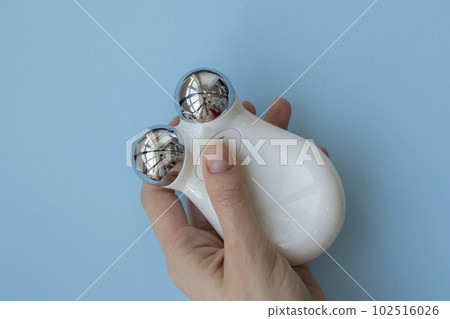 Microcurrent device in the hand on a blue background. Modern cosmetic treatment Microcurrent device in the hand on a blue background. Modern cosmetic treatment 102516026