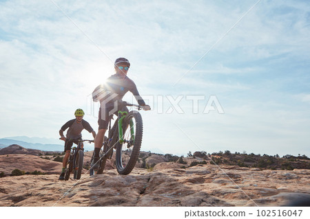 Fit is a journey not a destination. Full length shot of two athletic men mountain biking through the wilderness. 102516047
