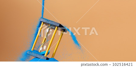 Hourglass is money sand of time, business pouring blue sand into hourglass to add more time in financial. Deadline extended time management hope concept to gold hour glass. Orange background sunset 102516421