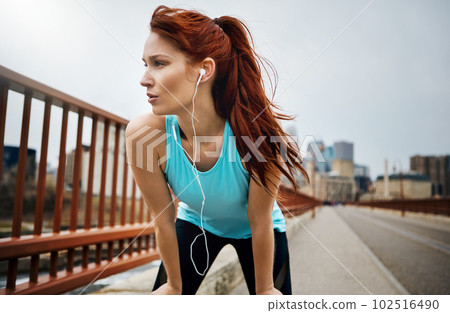 Dont stop until you feel yourself getting stronger. a sporty young woman taking a break while running in the city. 102516490