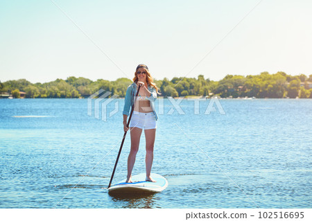 This is my kinda adventure. an attractive young woman paddle boarding on a lake. 102516695