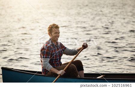 Finding peace on the lake. a young man rowing a boat out on the lake. 102516961