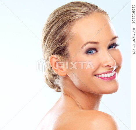 Dazzling smile. Studio shot of a beautiful young woman with perfect skin against a blue background. 102516972